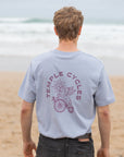 Unisex cotton tee in light blue, beach setting.