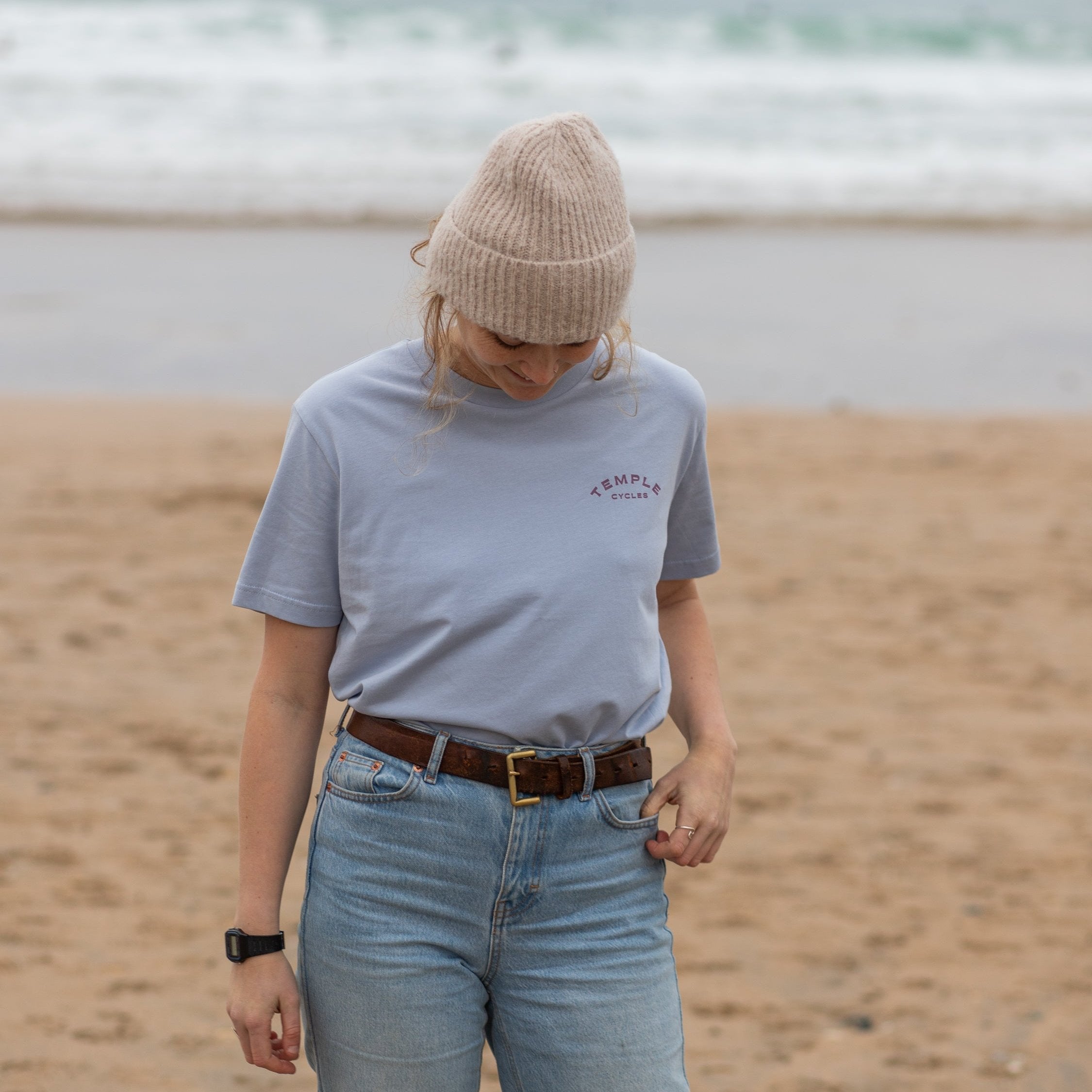 Female model facing camera with Temple Cycles super soft graphic tee in blue.