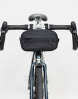 Front view of premium cycling bag in black attached to bike handlebars, studio setting.