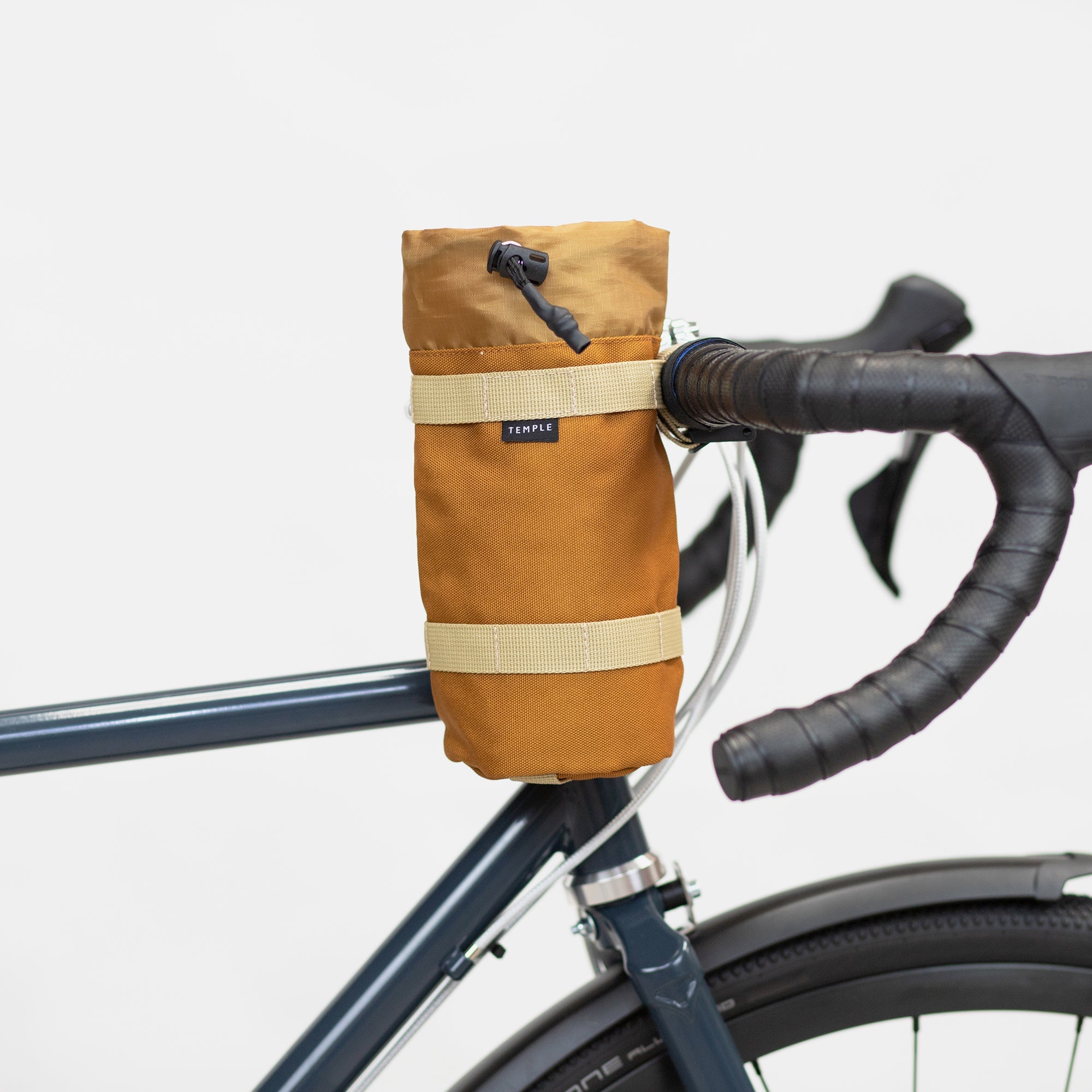 Un-rolled Temple snack bag attached to bicycle handlebars, studio setting. 