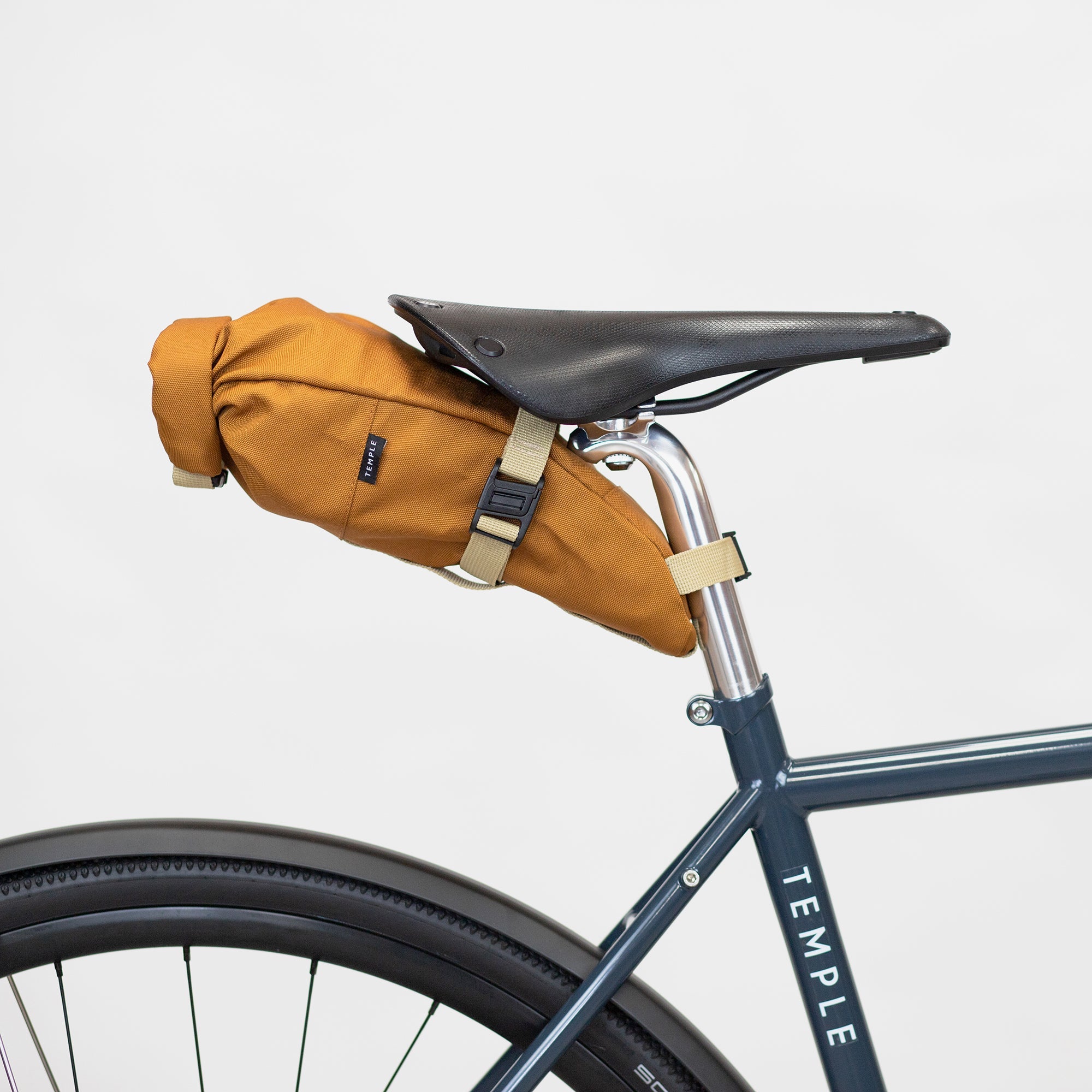 Temple orange saddle bag attached to bike seat, studio setting. 
