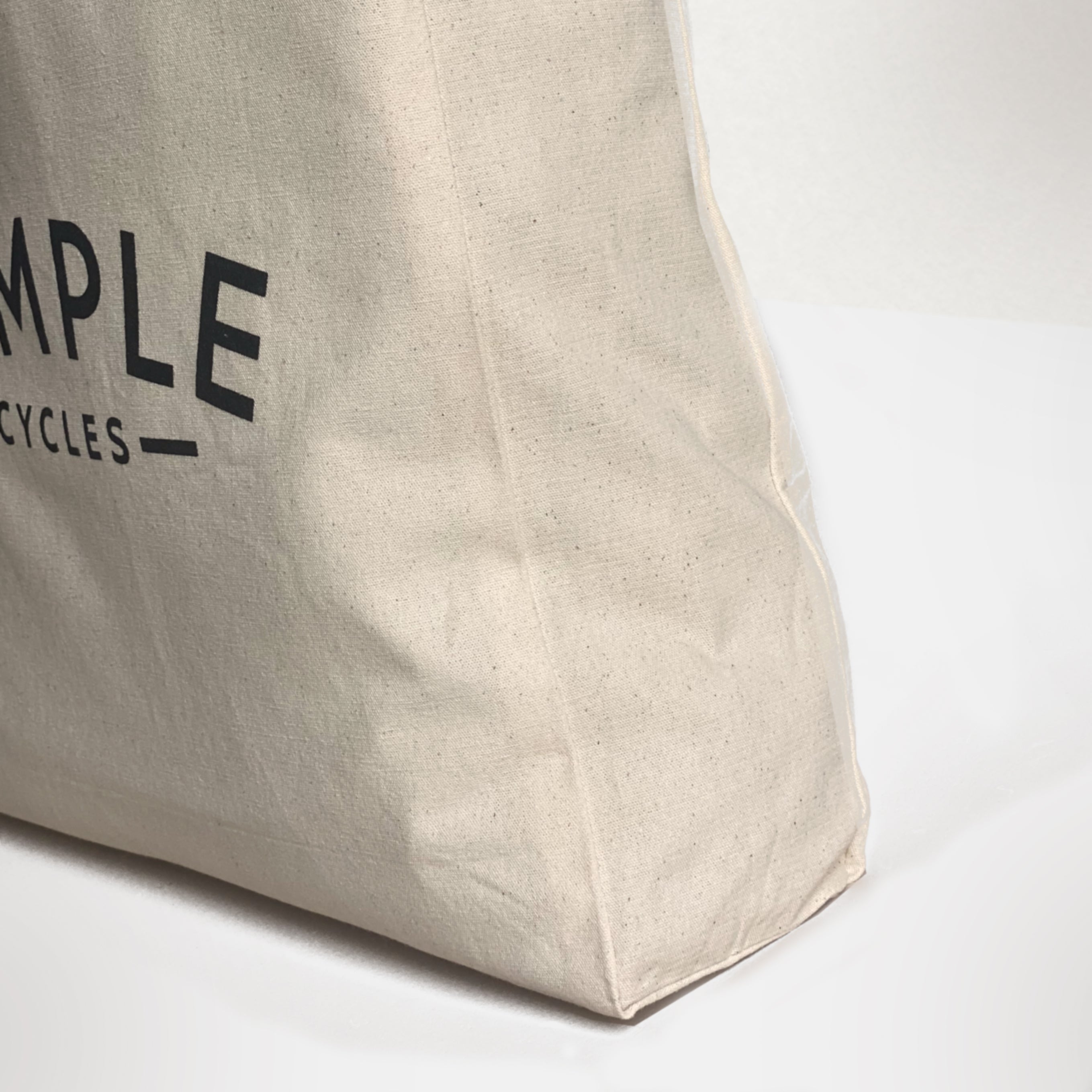 Heavyweight, beige tote bag with Temple logo, studio setting. 