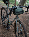 Bikepacking bag with Temple bar bag in green attached, forest setting.