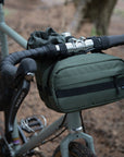 Versatile, waterproof cycling bar bag in green, forest setting.