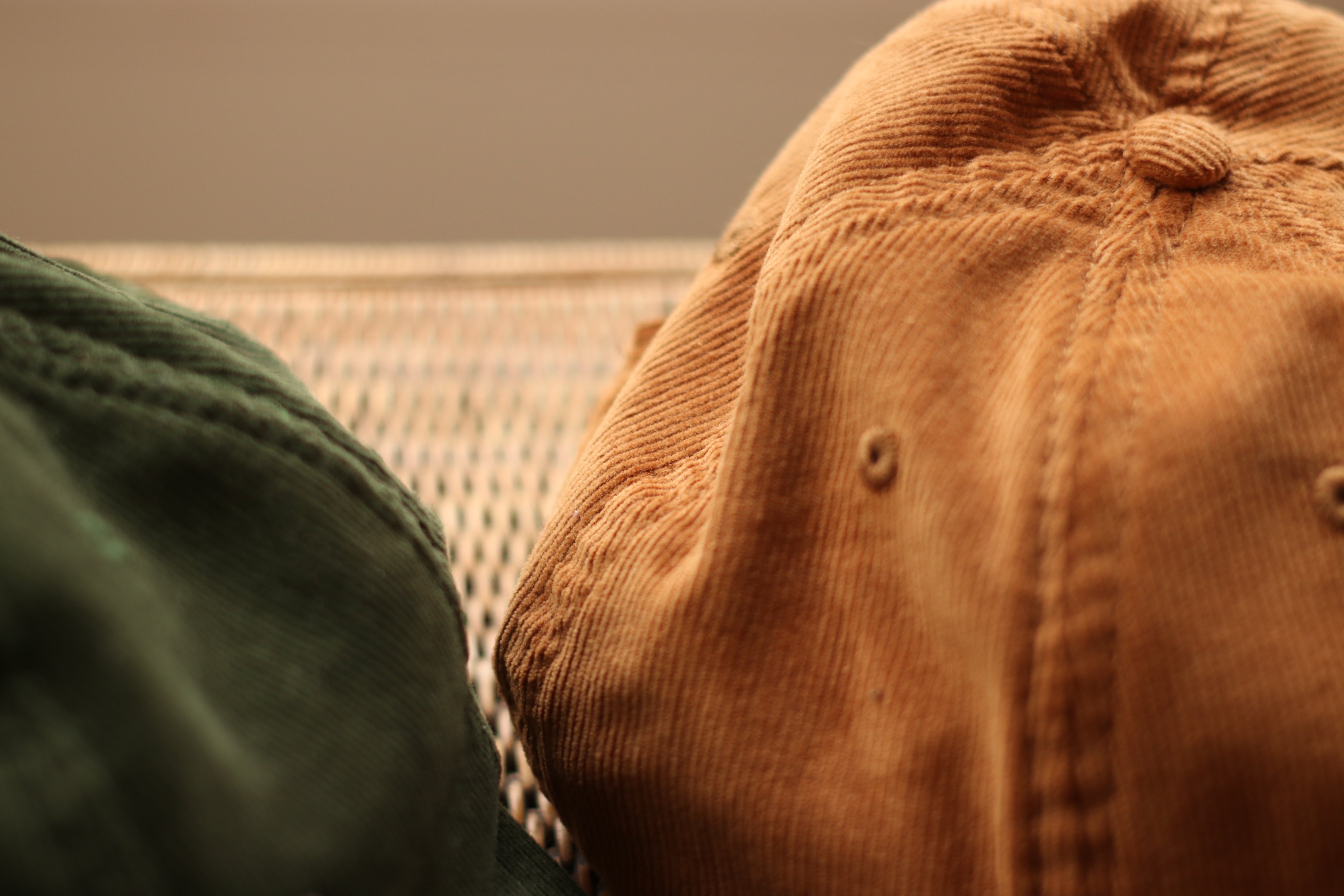 Adjustable men’s cap in green and brown, in-door setting. 