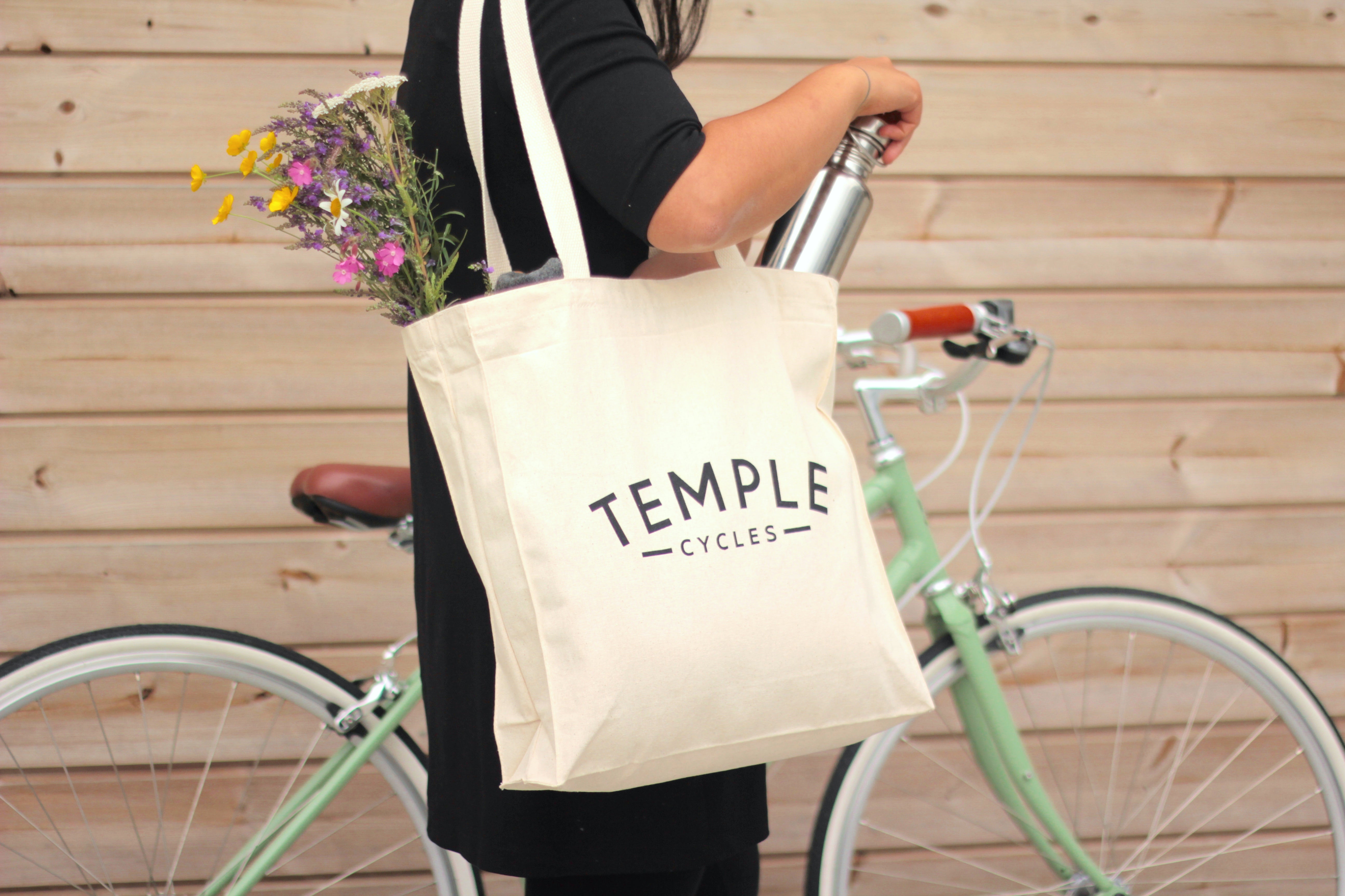 Model using casual canvas tote bag, urban setting.