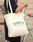 Model using casual canvas tote bag, urban setting.