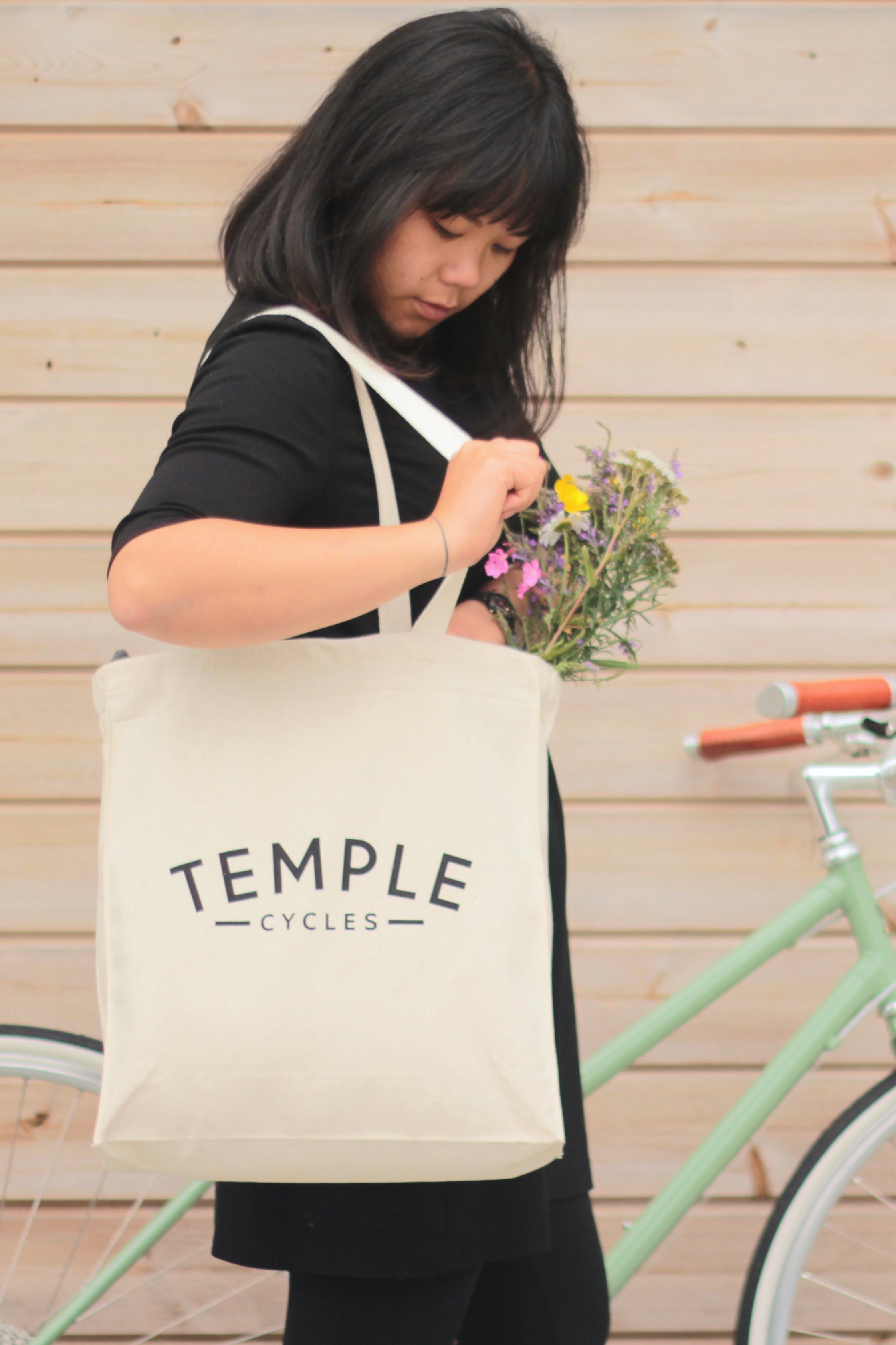 Model reaching into heavyweight cotton shopper bag with flowers.