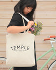 Model reaching into heavyweight cotton shopper bag with flowers.