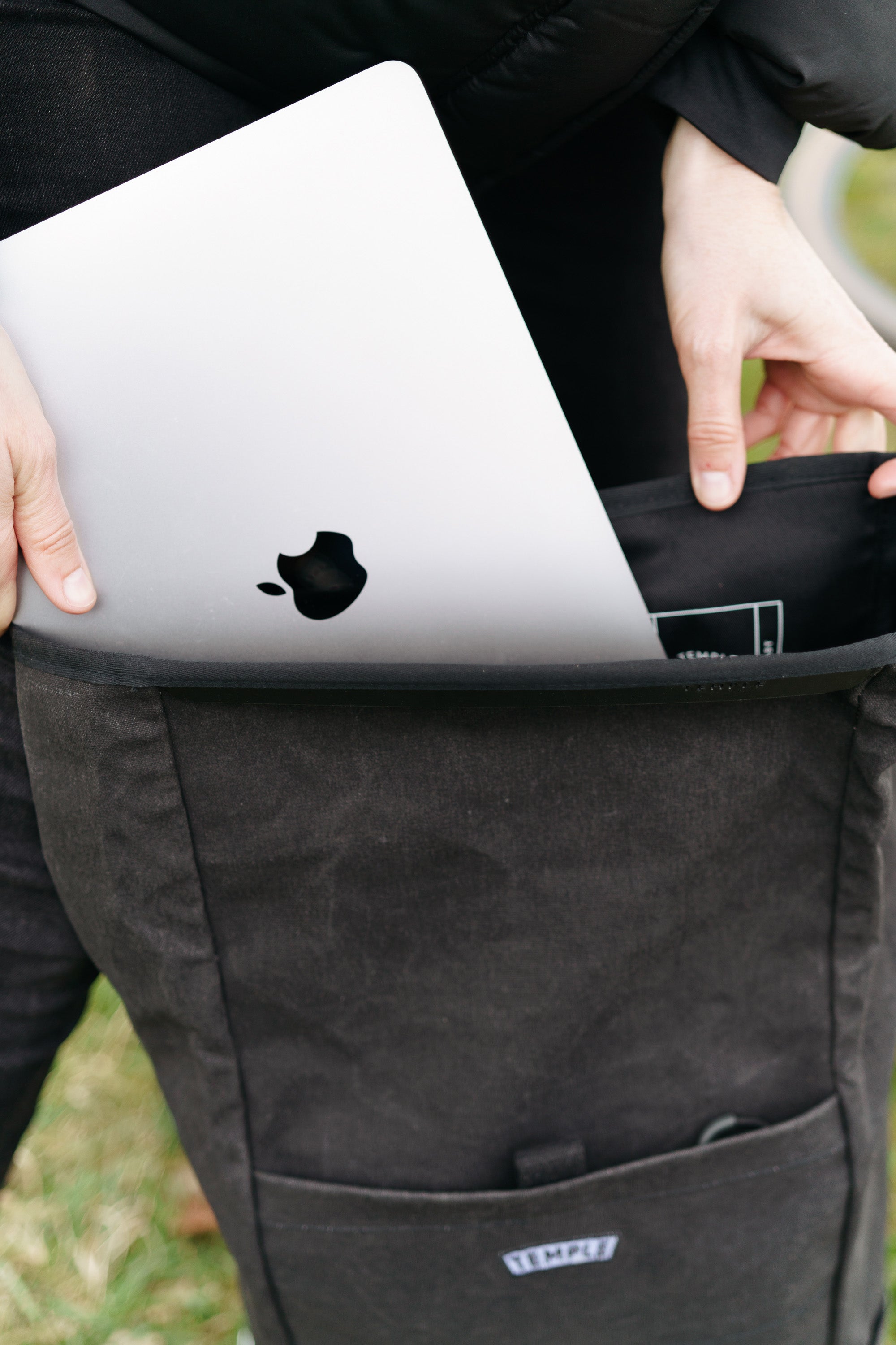 Model placing laptop into interior pannier sleeve in a rural setting.