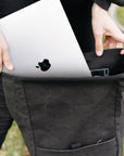 Model placing laptop into interior pannier sleeve in a rural setting.