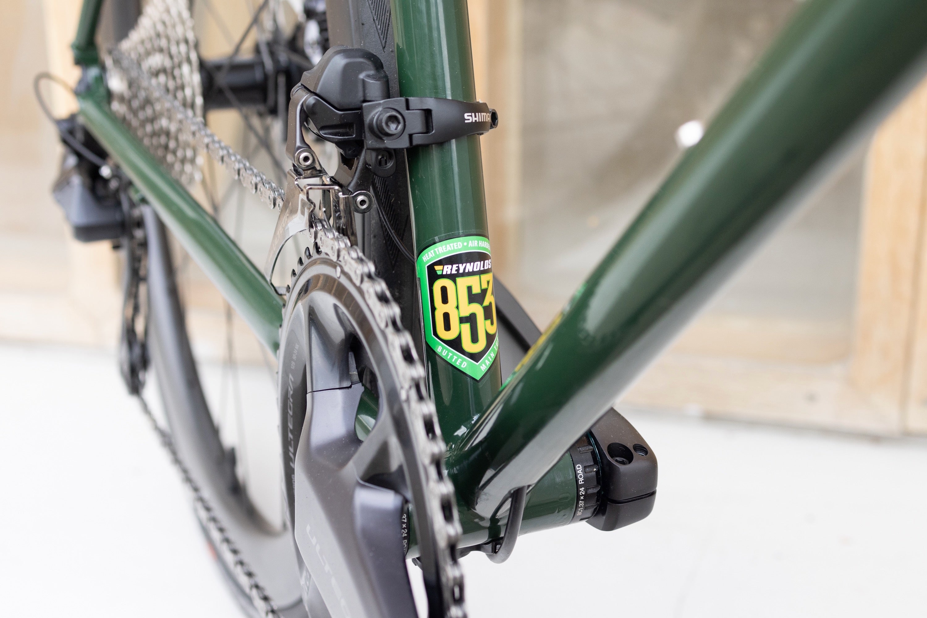 Reynolds 853 steel frame emblem and Shimano chainset on a dark green road bike.
