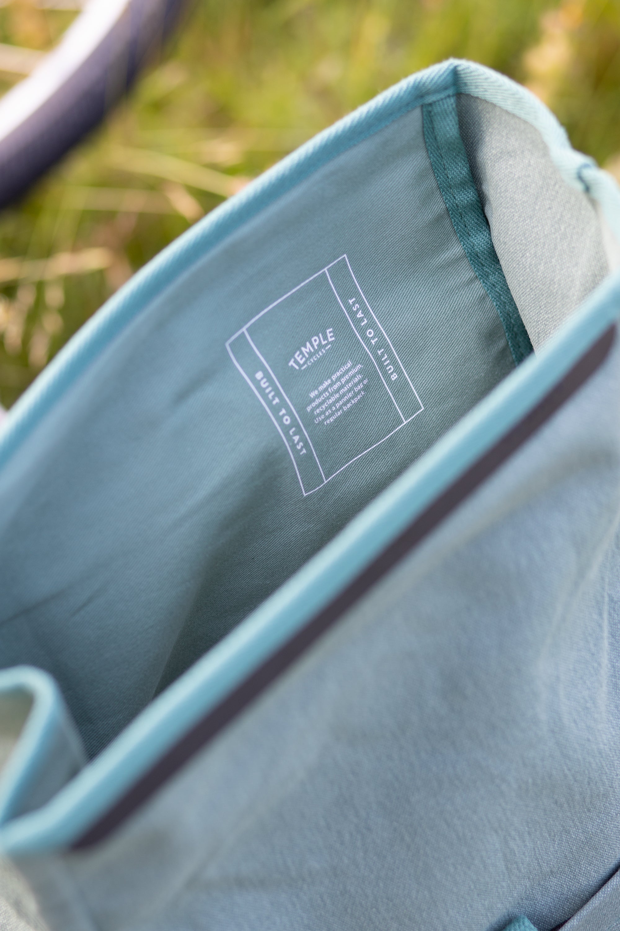 Interior Temple Cycles spec detail on a waterproof teal backpack, rural setting.