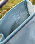 Interior Temple Cycles spec detail on a waterproof teal backpack, rural setting.