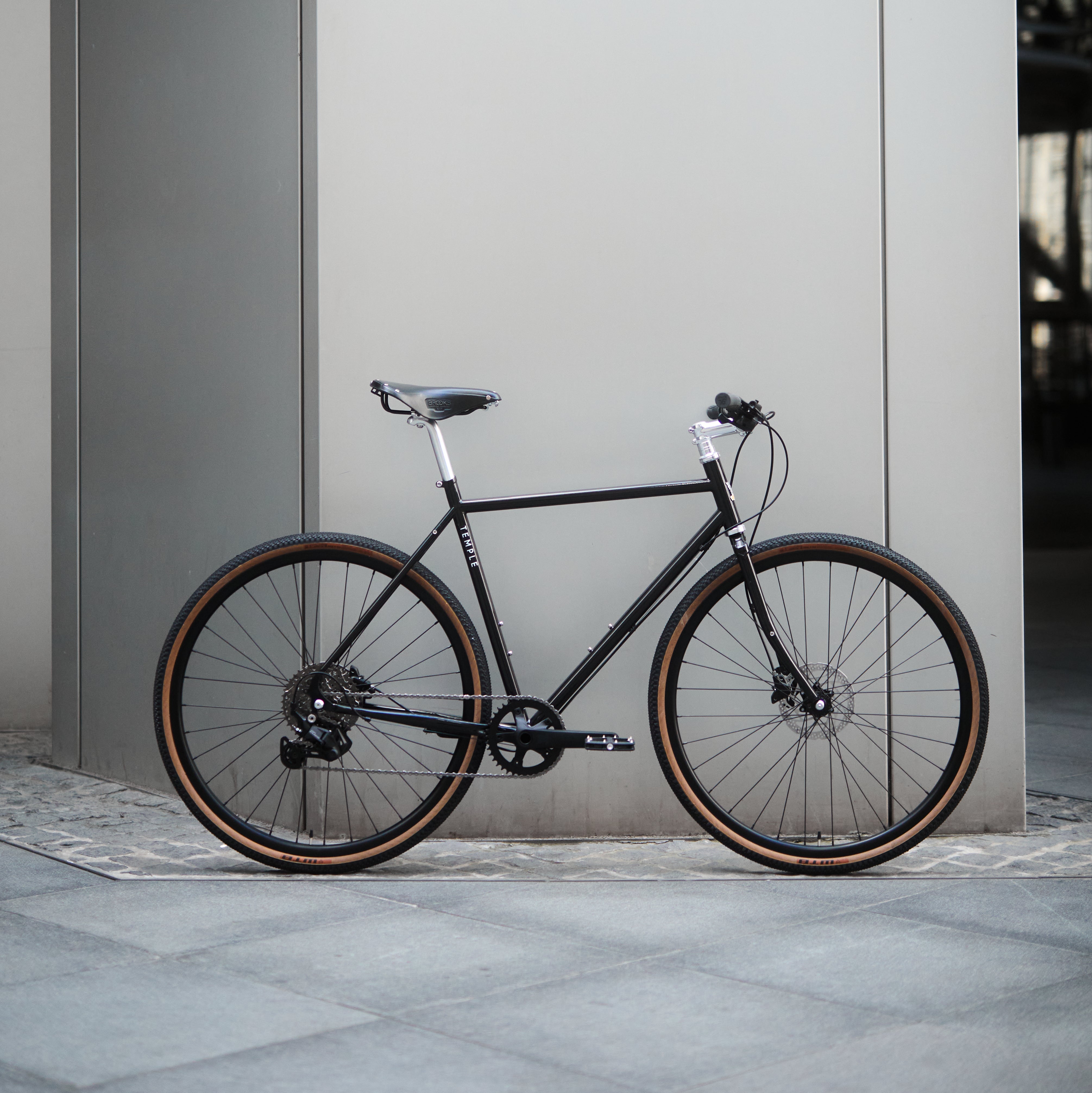 Black bicycle leaning against a gray wall.