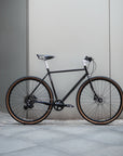 Black bicycle leaning against a gray wall.