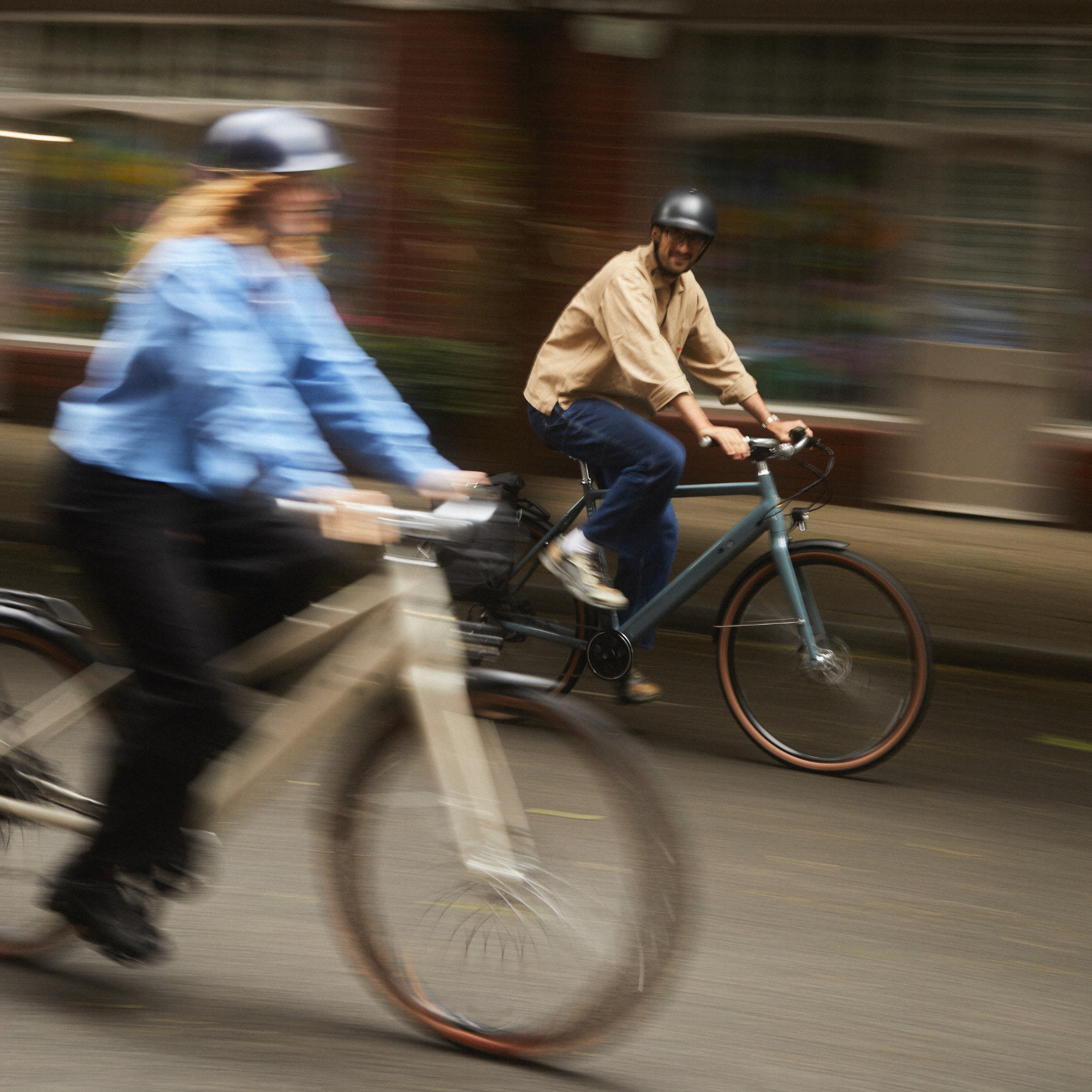 Two people riding bicycles on a city street with blurred motion