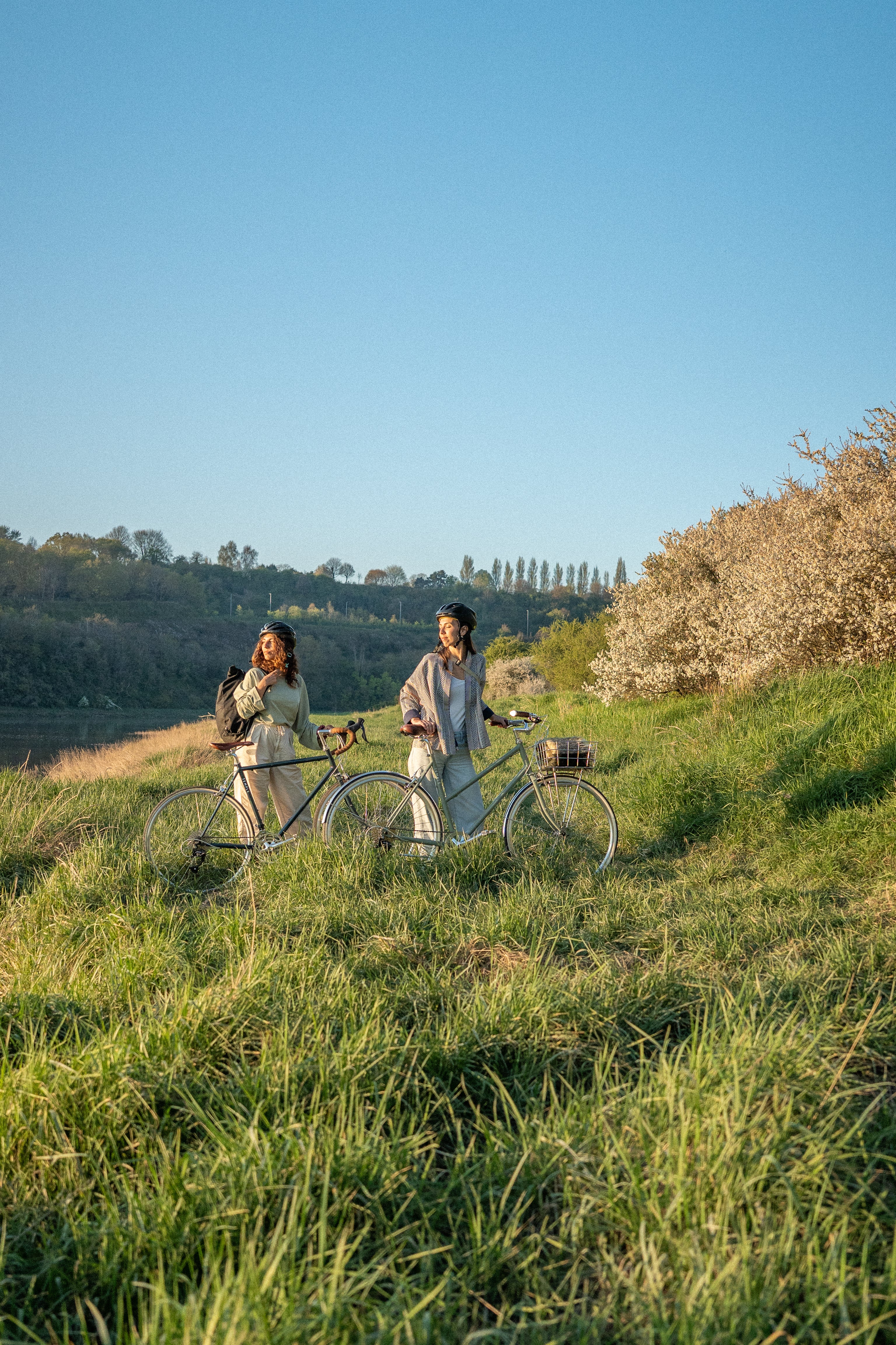 Two women with bicycles in a scenic outdoor setting
