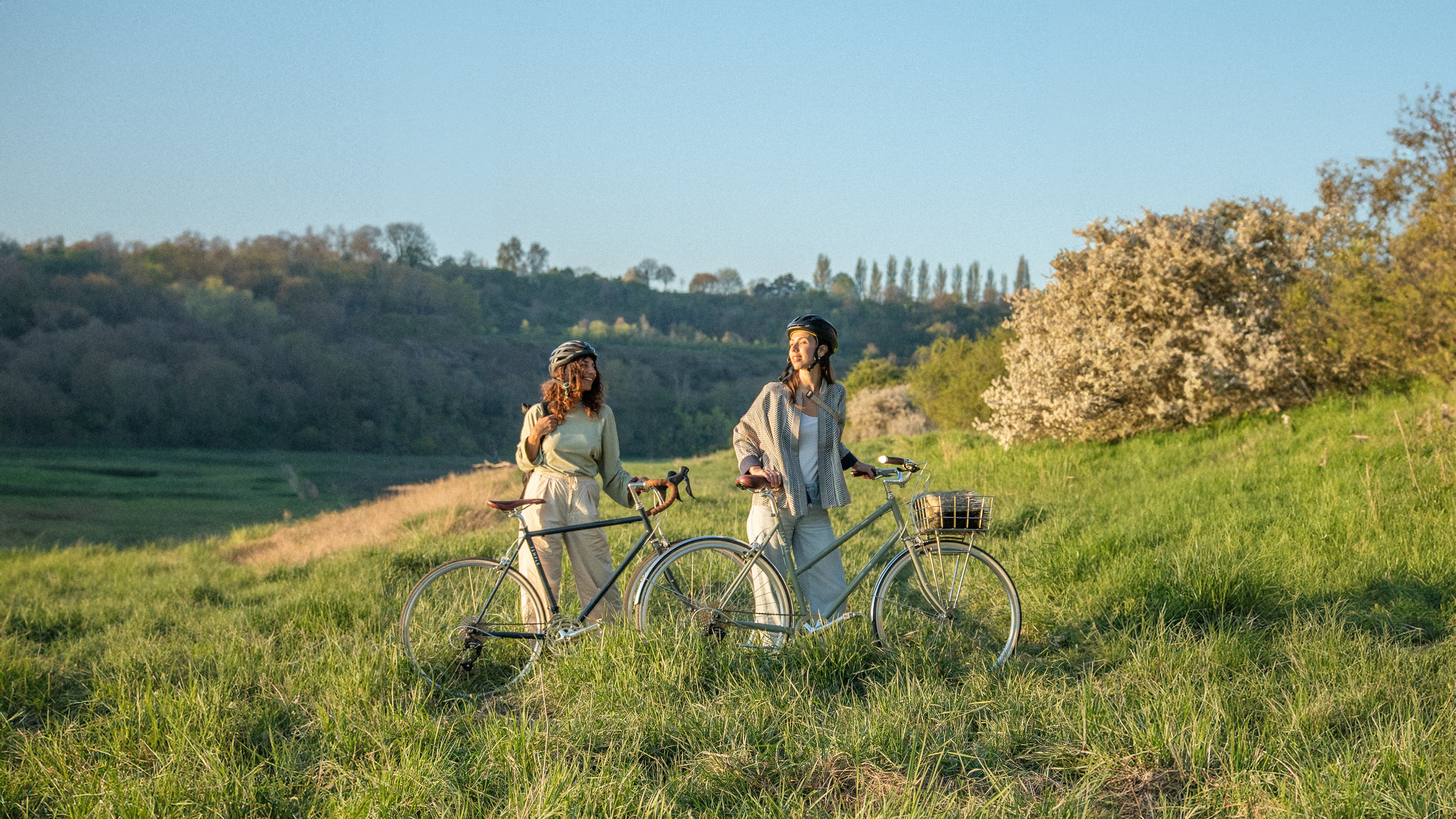 Two women with bicycles in a scenic outdoor setting