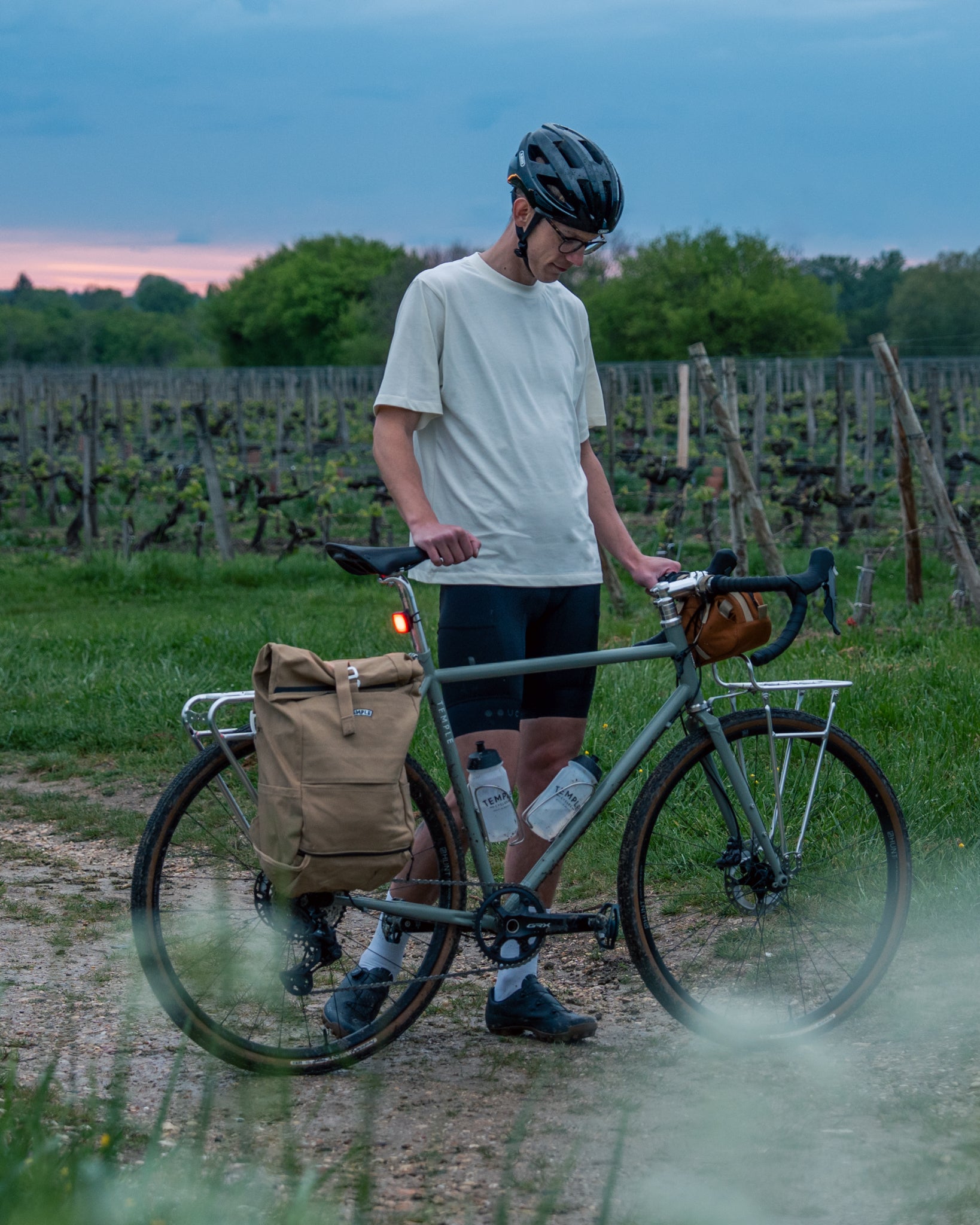 Person with a bicycle in a vineyard at dusk