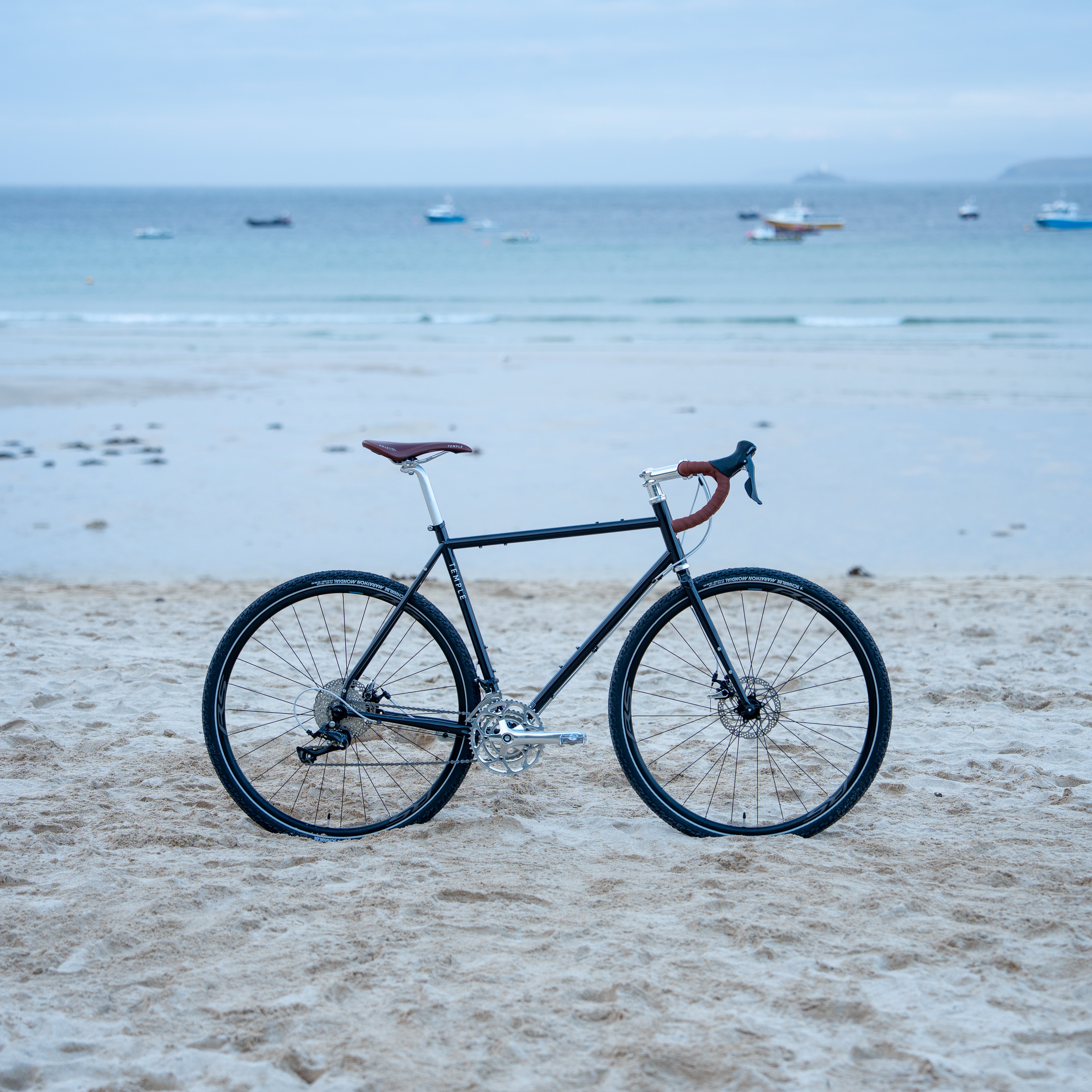 Bicycle on a sandy beach with boats in the water