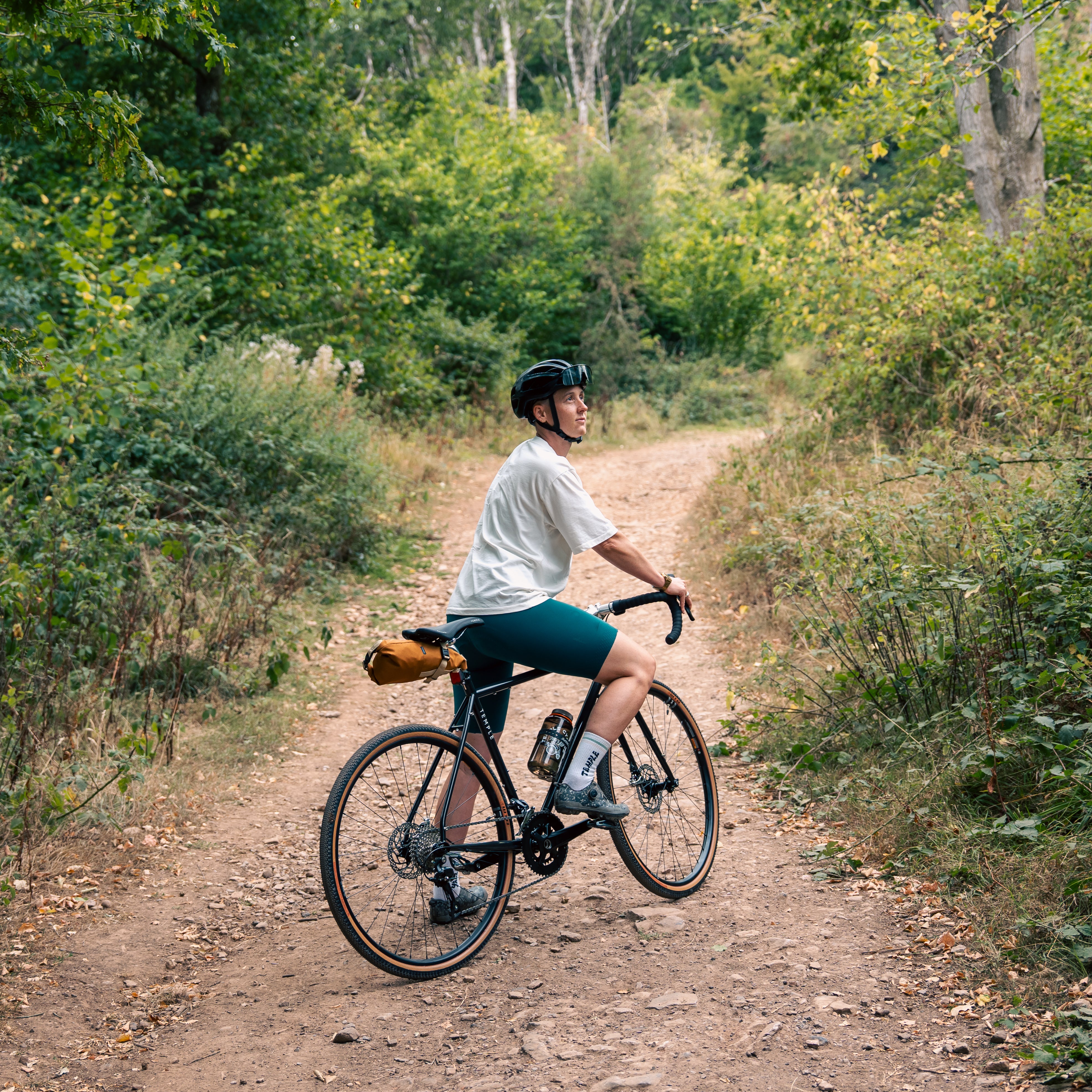 Person riding a bicycle on a dirt path in a forest