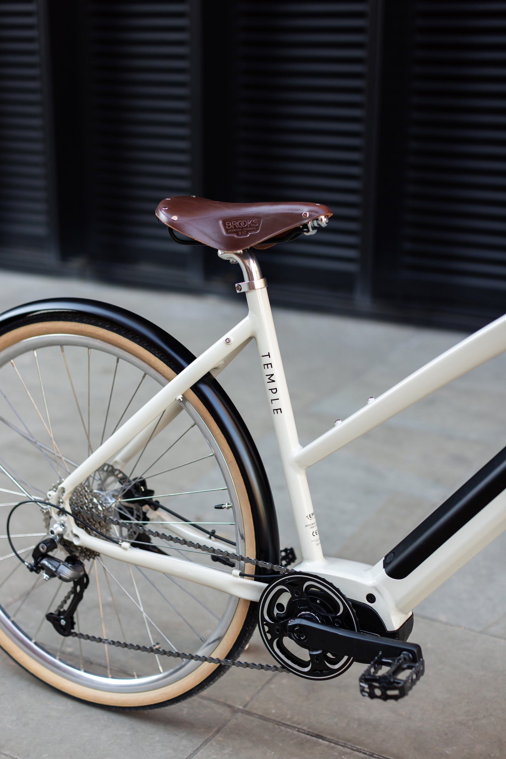 Rear wheel, with wide-ranging Shimano gears on a minimalist cream electric bicycle. 