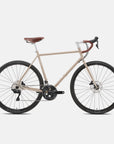 Beige lightweight steel adventure bike in a studio setting.