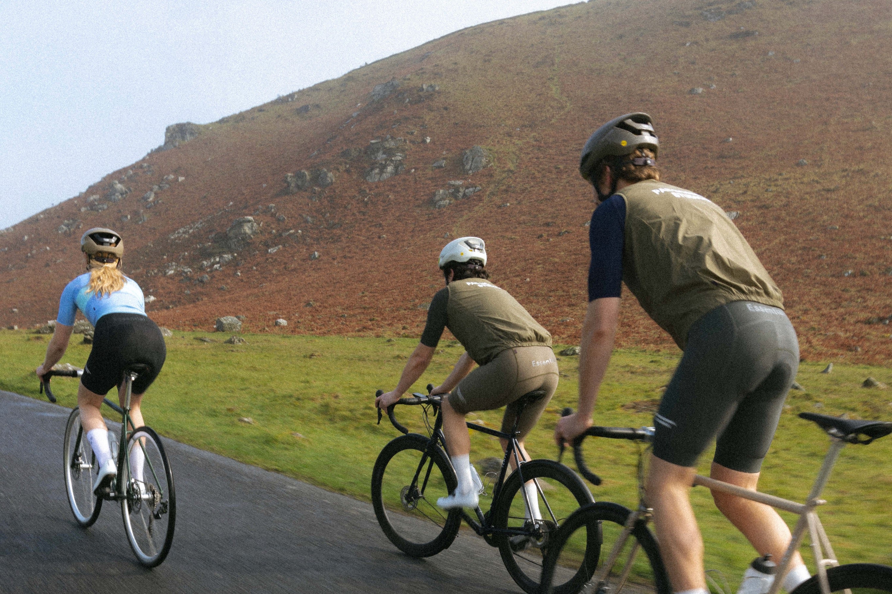 Three cyclists riding through mountainous scenery on lightweight, durable road bikes.
