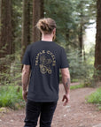 Men’s subtle style navy graphic T Shirt, back view, forest setting. 