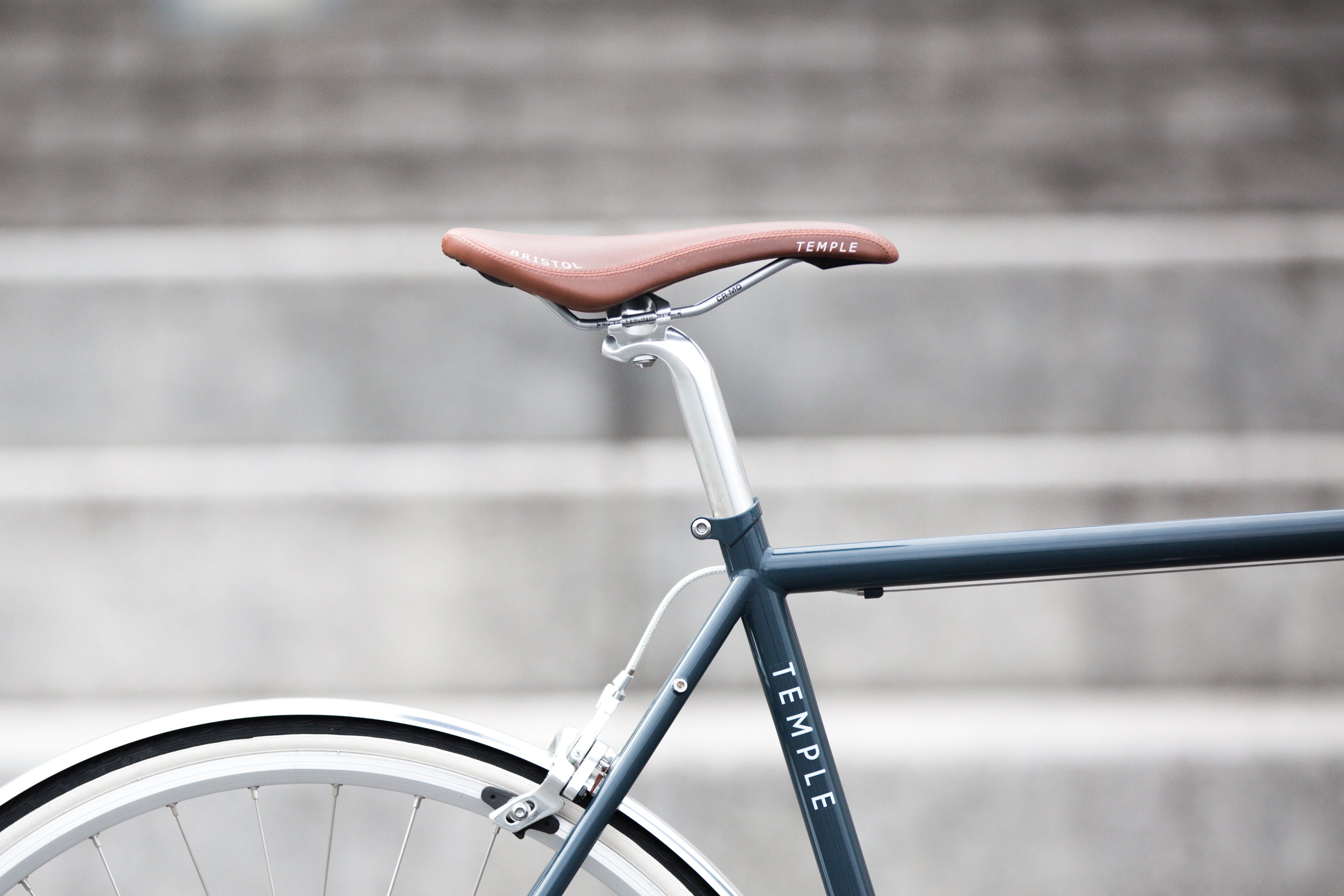 Temple Bristol leather saddle on a steel lightweight hybrid bike, urban setting.