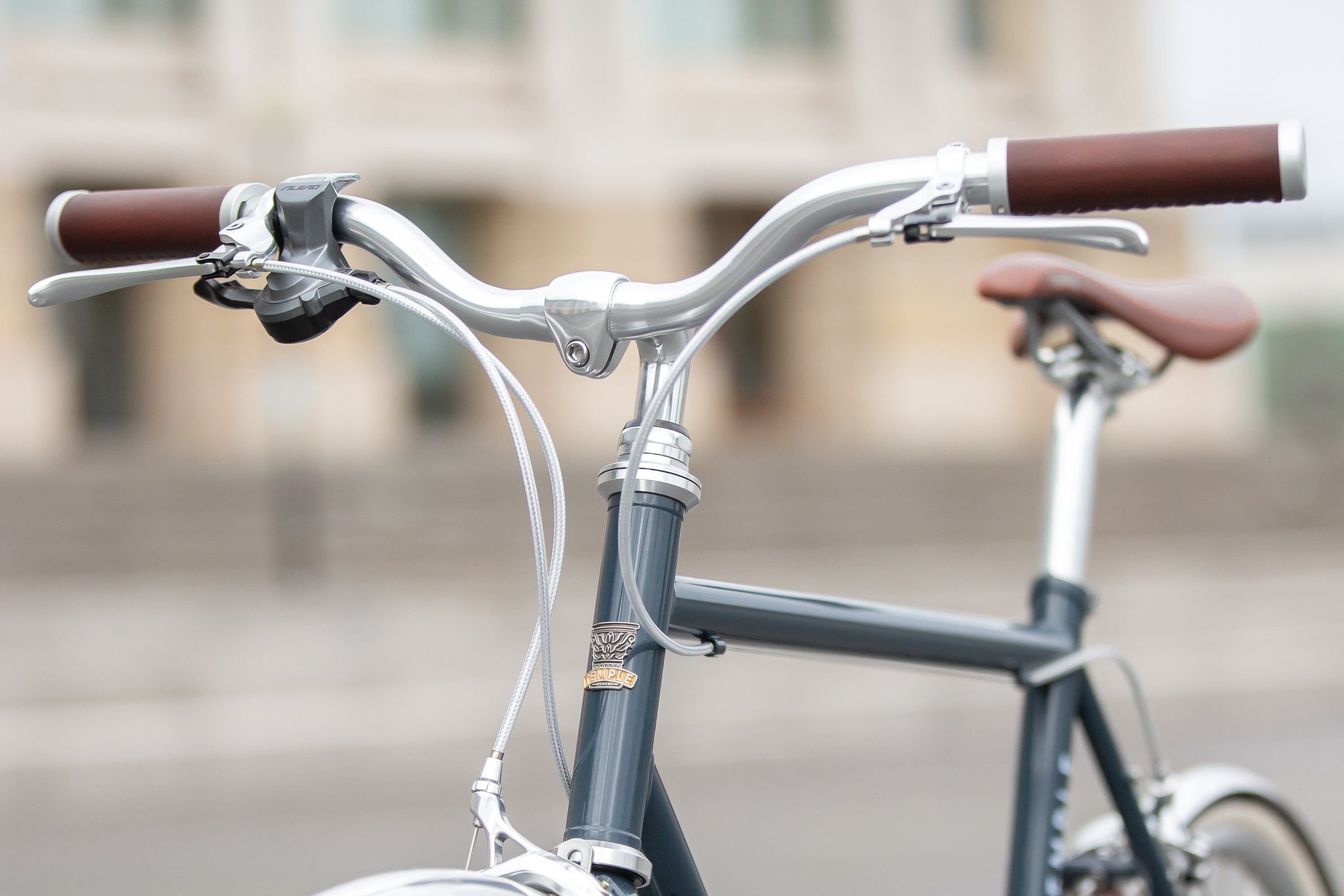 Silver braided brake cables and classic Temple handlebars on a blue daily commuter bike.