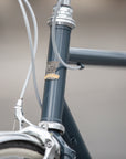 Temple head badge on blue steel head tube of a classic lightweight touring bike.