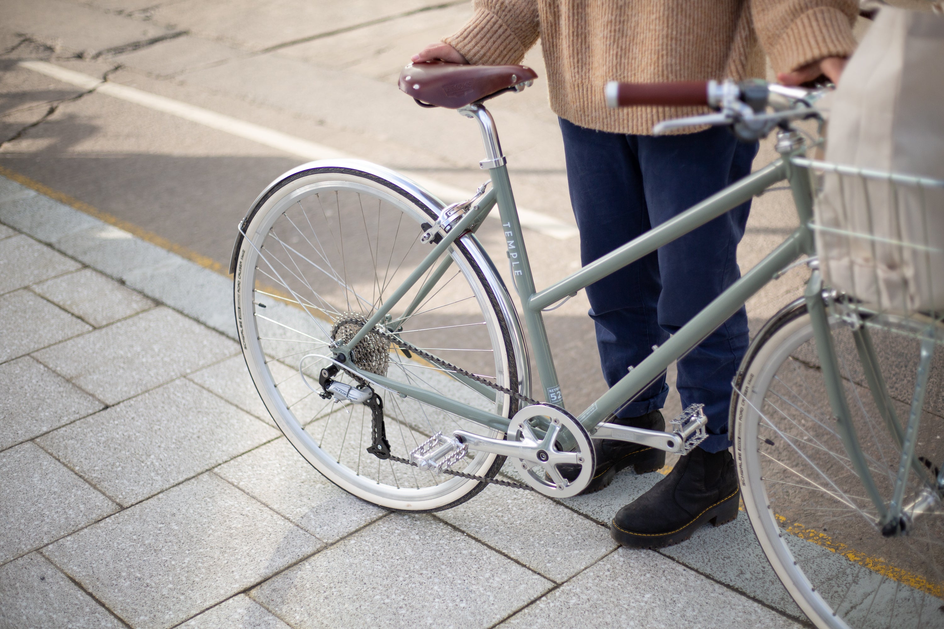 Model holding green Step through lightweight commuter bicycle in an urban setting.