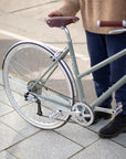 Model holding green Step through lightweight commuter bicycle in an urban setting.