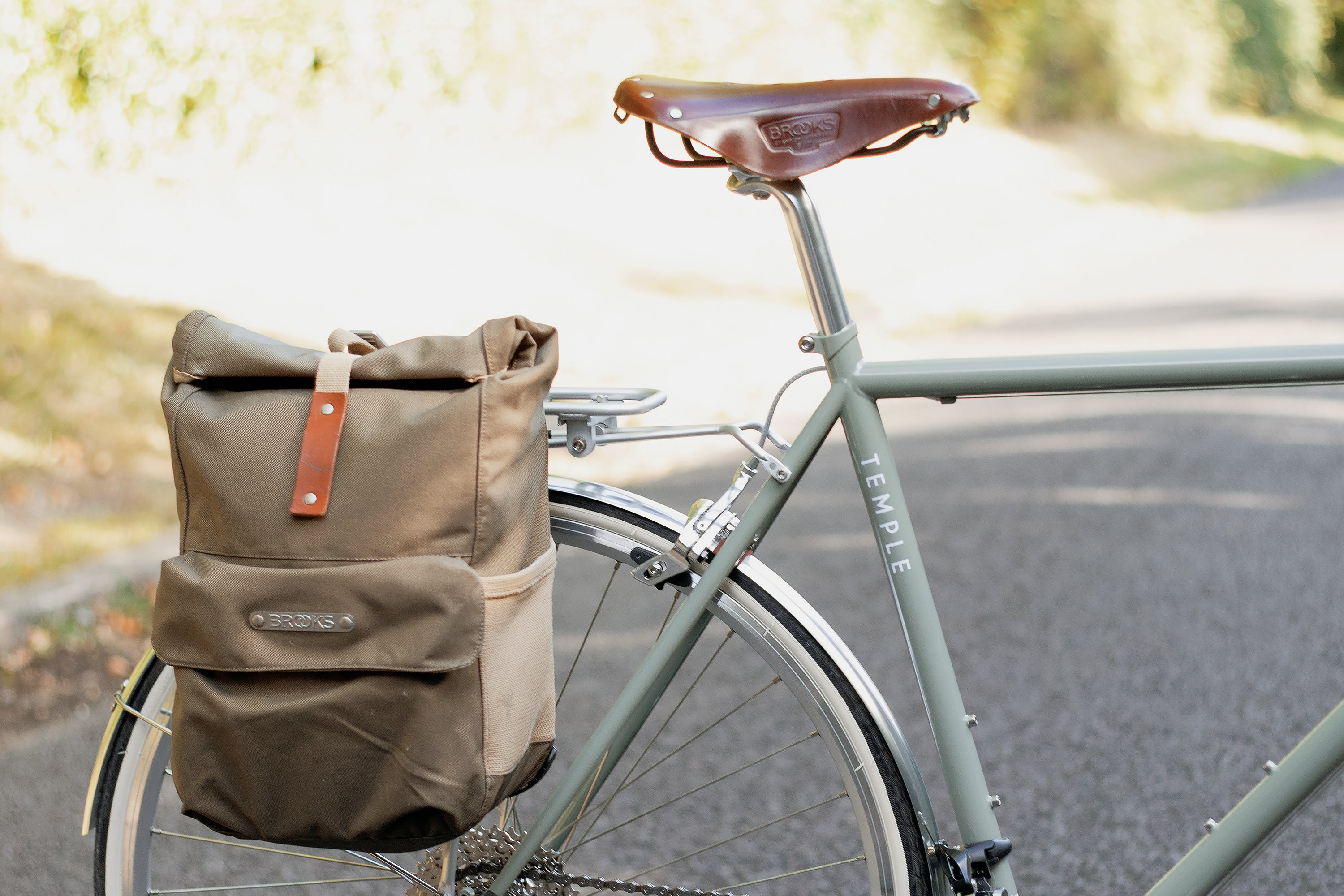 Beige pannier backpack on lightweight steel touring bicycle in a rural setting.