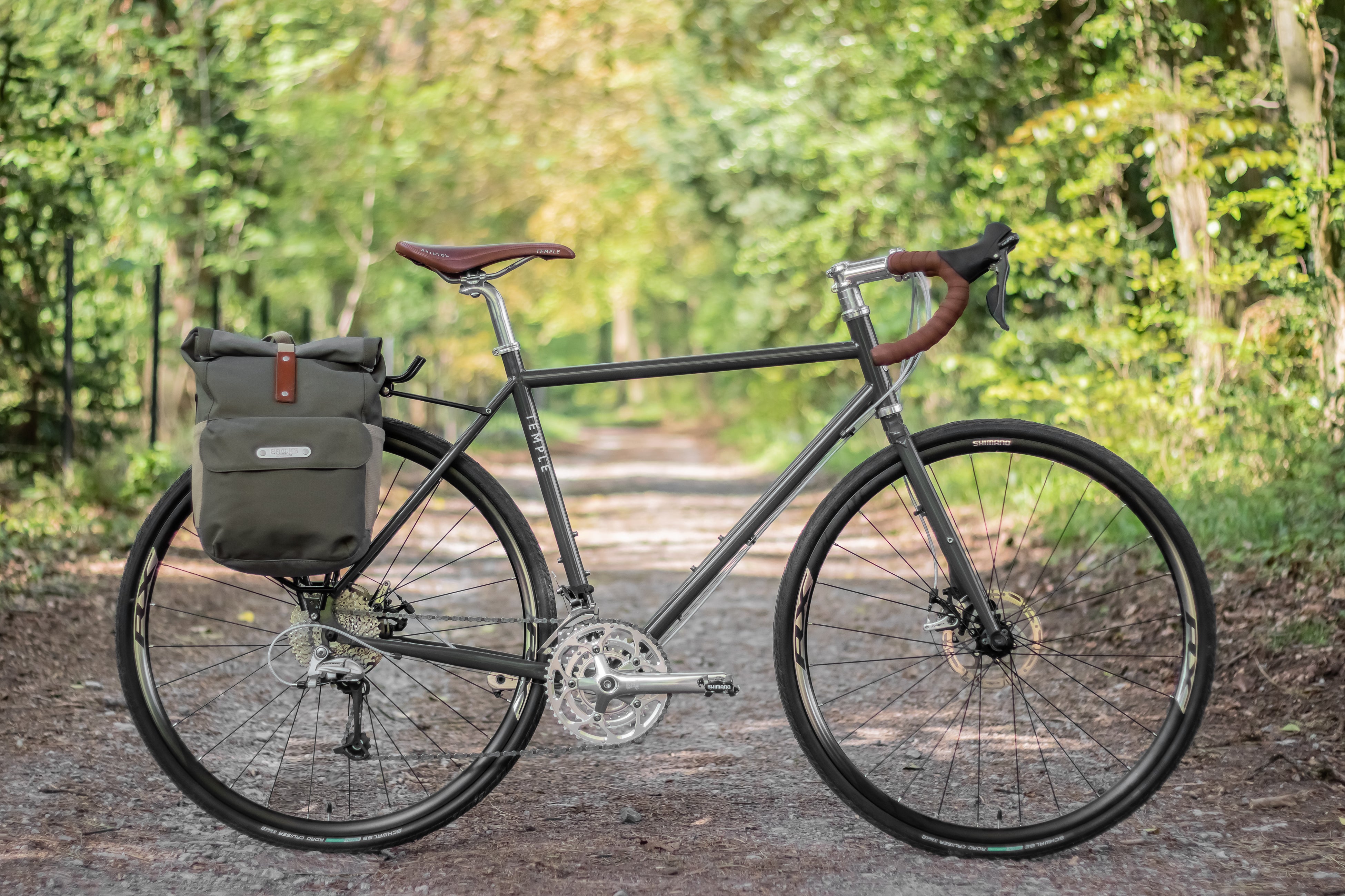 lifestyle racing-green adventure gravel bike with a pannier backpack, forest setting.