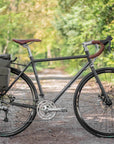 lifestyle racing-green adventure gravel bike with a pannier backpack, forest setting.