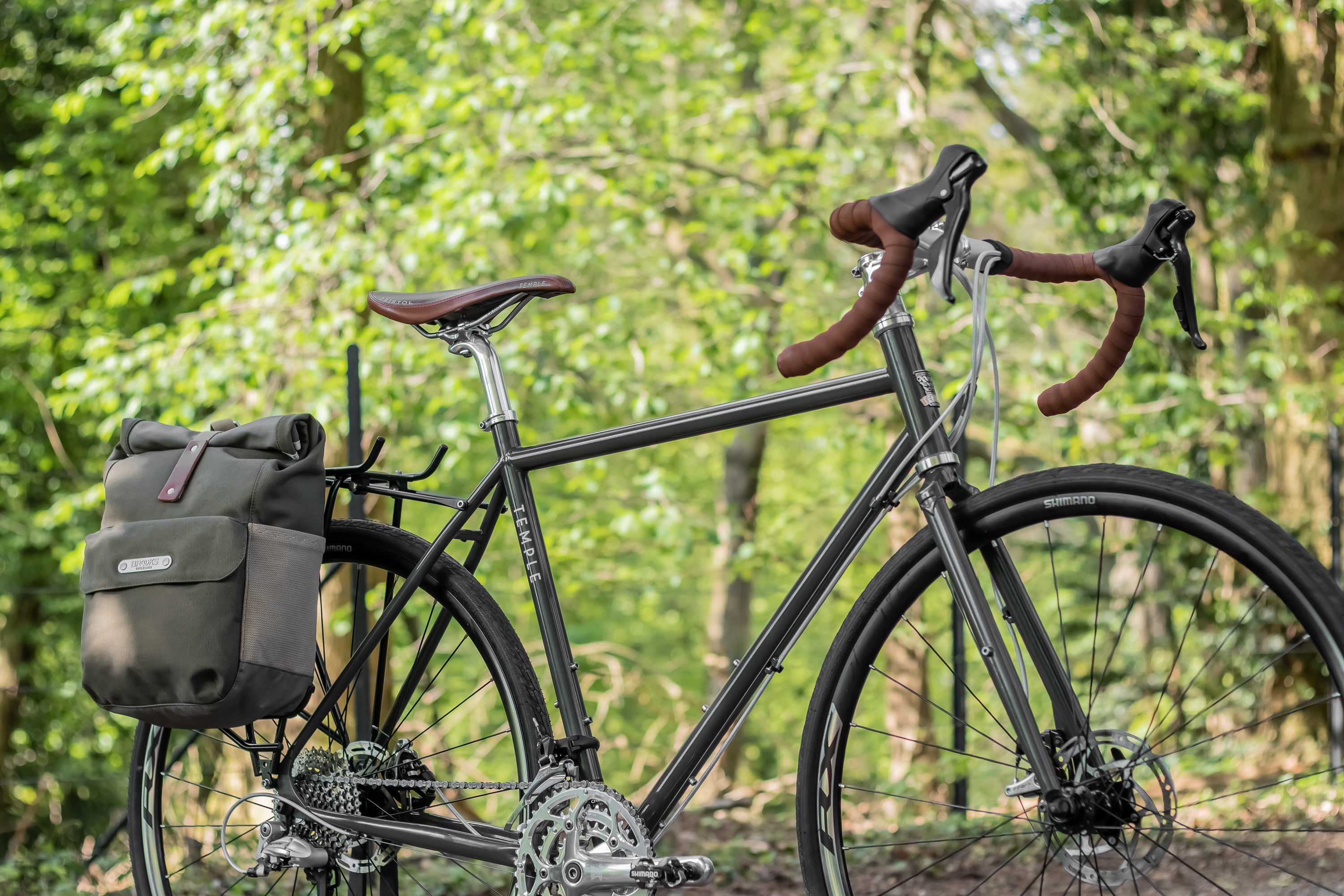 Limited edition adventure gravel bike in racing green with pannier backpack in a forest setting.