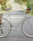 Green touring bike with pannier backpack in a rural setting.