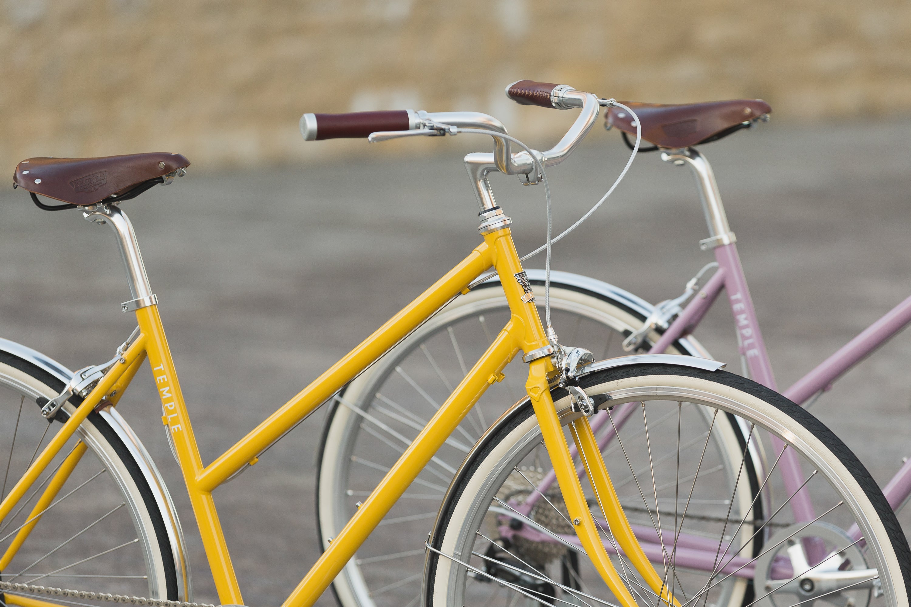 Two lightweight daily commuting bikes in yellow and pink, urban setting.